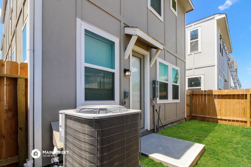 a backyard with a hot tub and a patio with a wooden fence