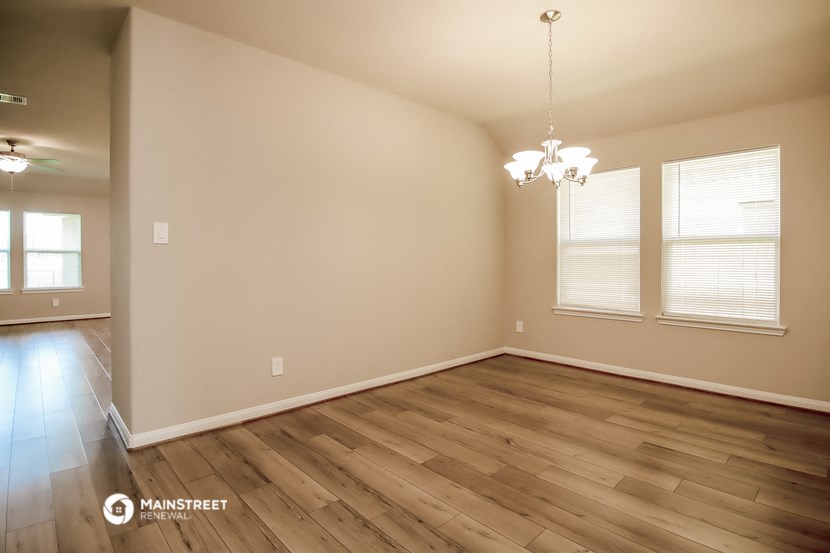 the spacious living room with hardwood flooring and windows