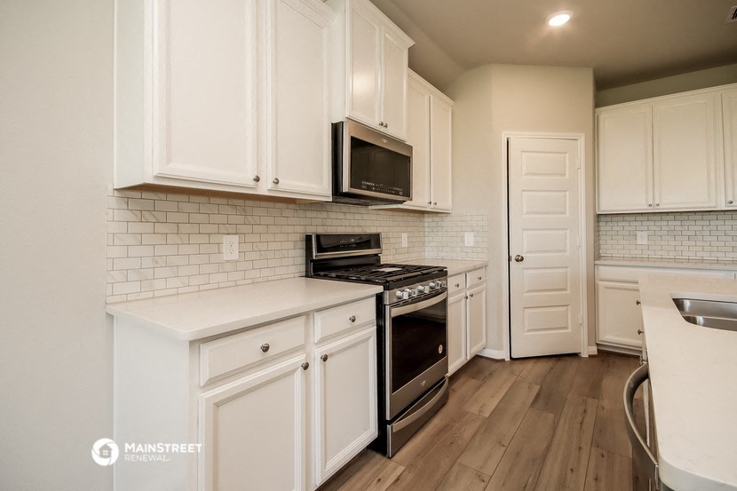 a kitchen with white cabinets and a stove and a microwave