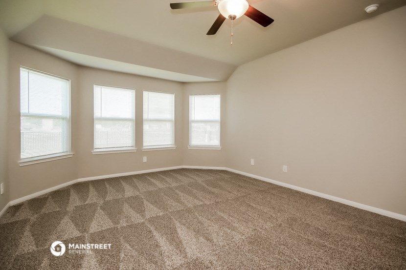 the spacious living room with windows and a ceiling fan
