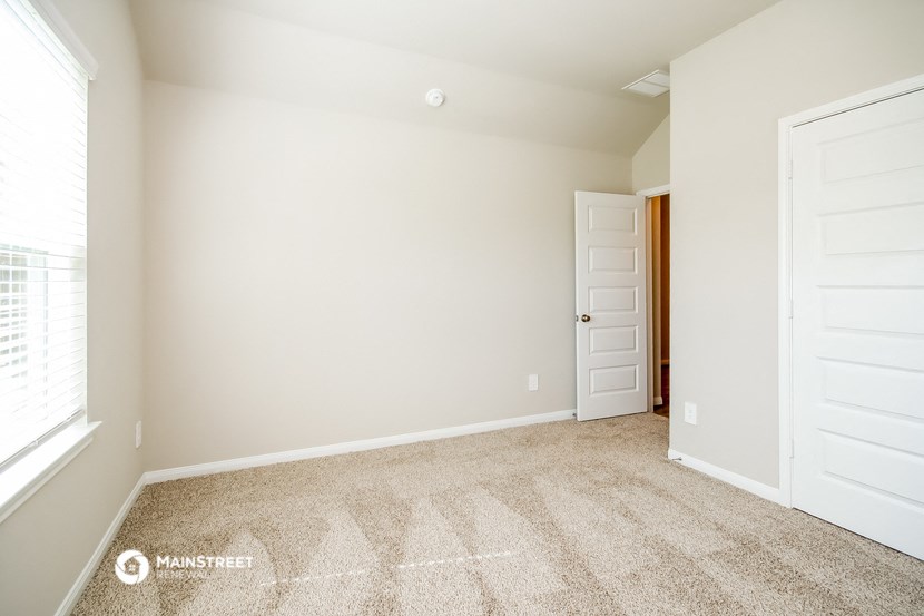 an empty room with carpet and a door to a closet