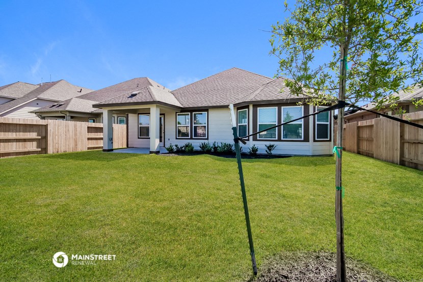 the backyard of a home with a lawn and a tree