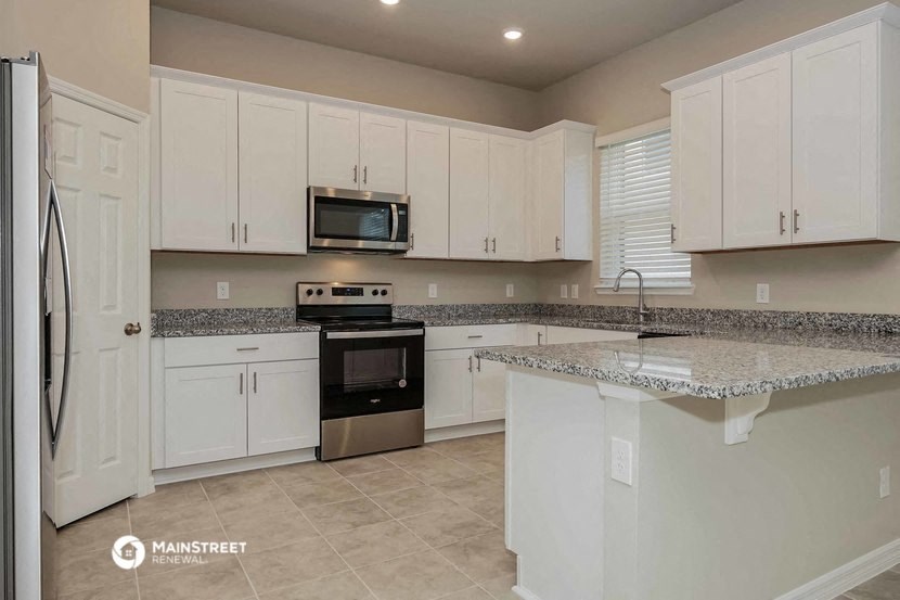 a large kitchen with white cabinets and granite counter tops