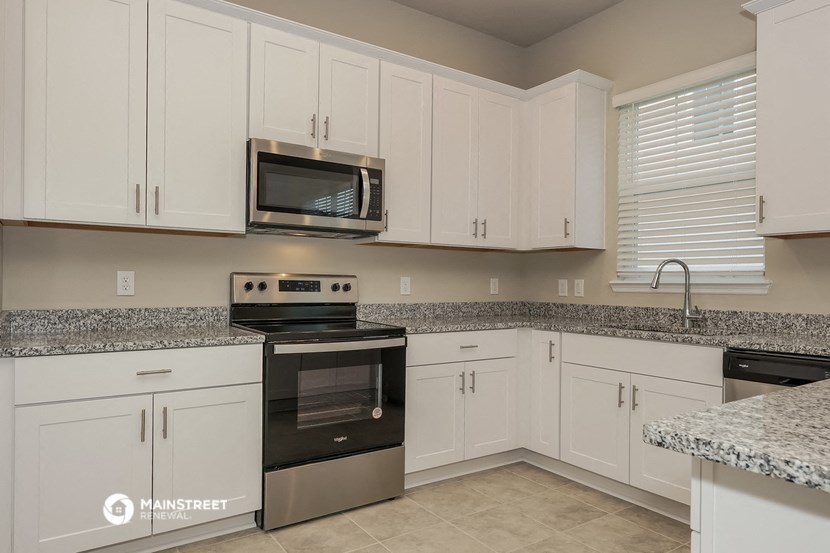 a kitchen with white cabinets and black appliances and granite counter tops