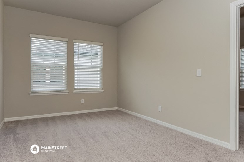 a bedroom with two windows and a carpeted floor