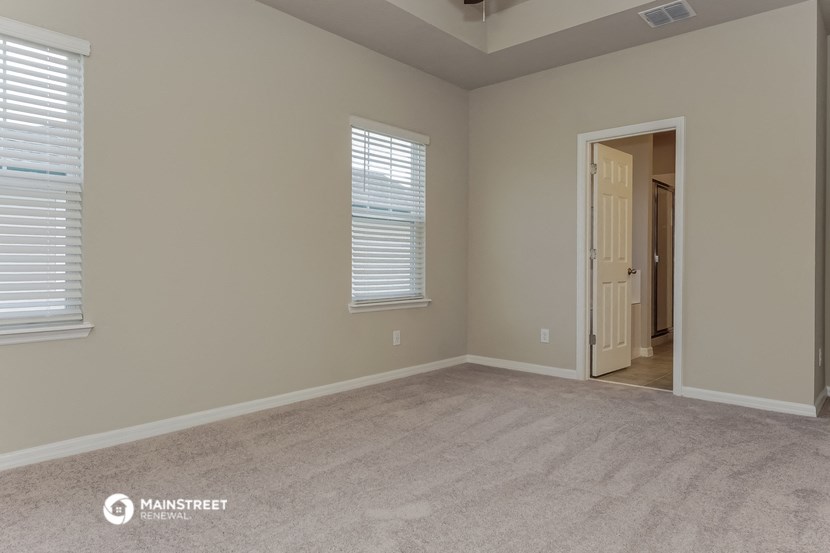 the spacious living room with carpeted flooring and a door to the hallway