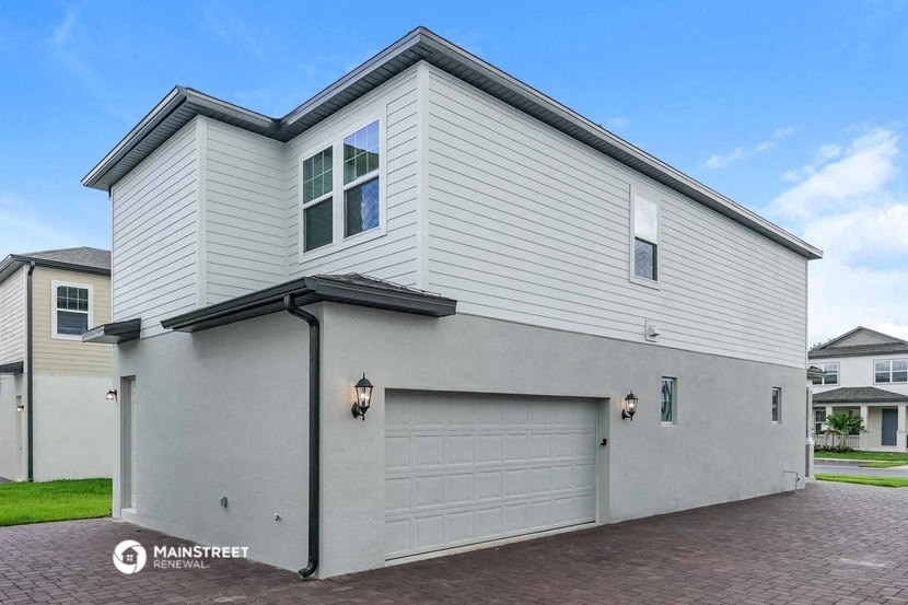 the front of a white house with a garage door
