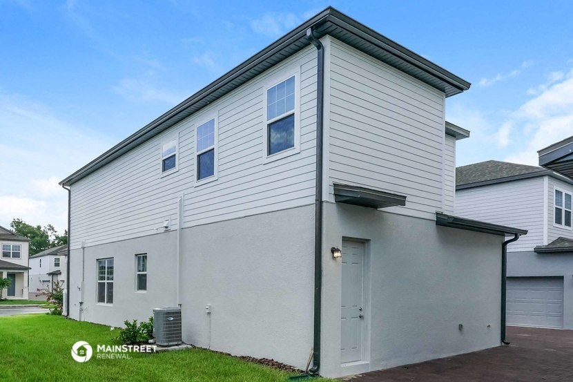 the front of a white house with a garage and grass