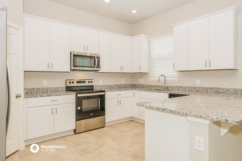 a kitchen with white cabinets and granite counter tops