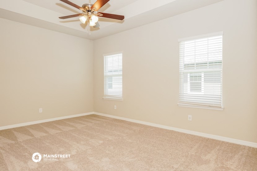 the spacious living room with carpeting and a ceiling fan