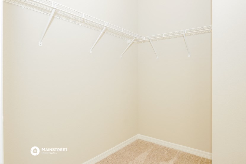 the spacious closet in the master bedroom of a manufactured home with white rods on the