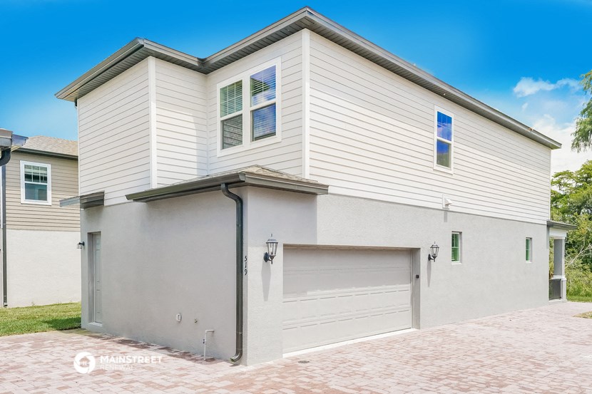 a white house with a white garage door and a brick driveway