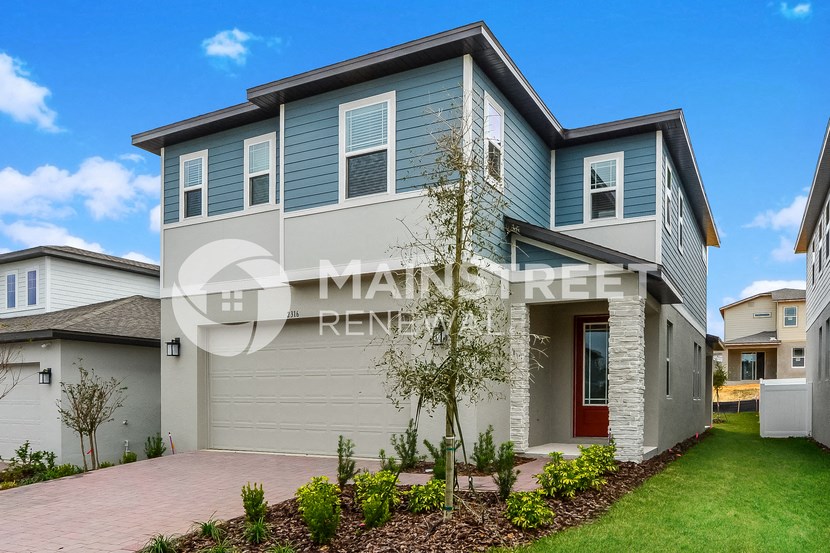a blue and white house with a driveway and grass