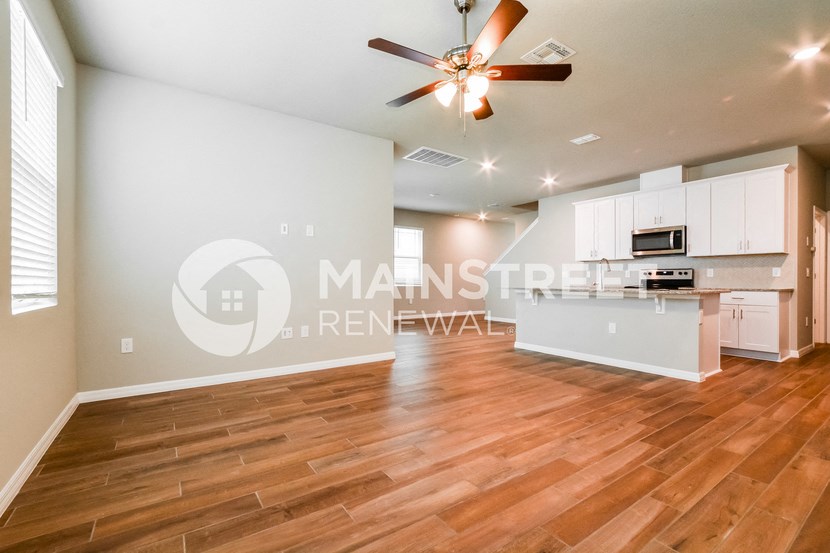 a large living room with a kitchen and a ceiling fan