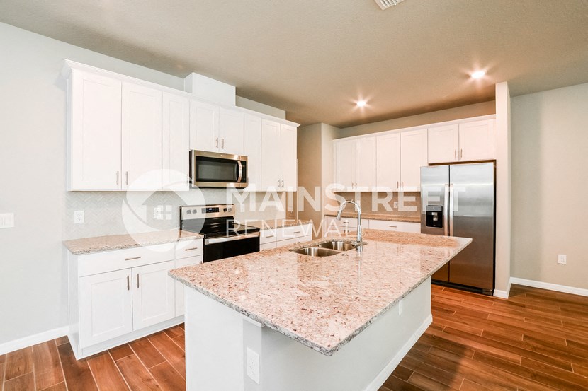 a kitchen with granite countertops and white cabinets and stainless steel appliances