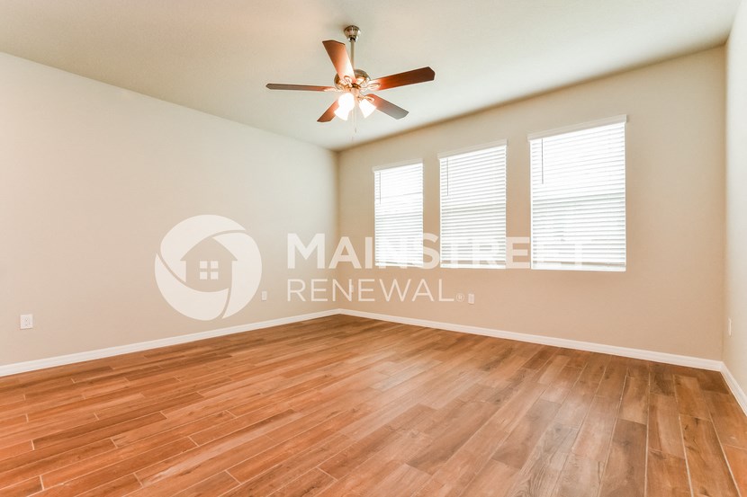 an empty living room with wood floors and a ceiling fan