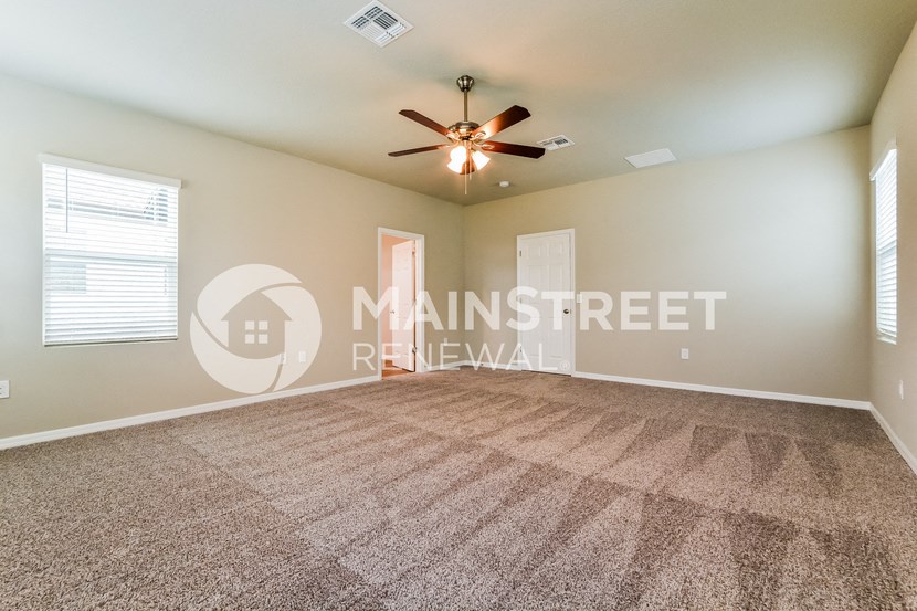 a living room with carpet and a ceiling fan