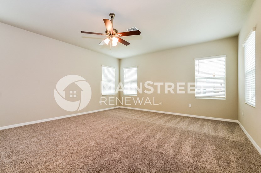 a living room with carpet and a ceiling fan