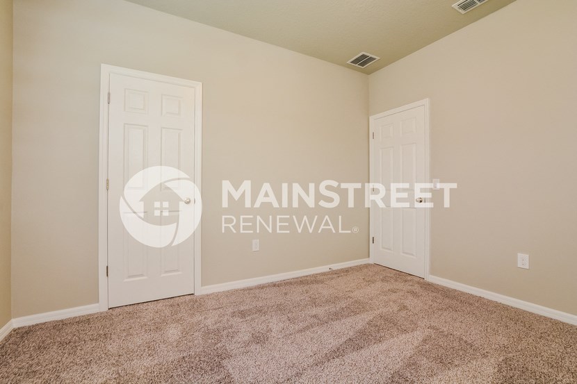 a bedroom with two doors and a carpeted floor