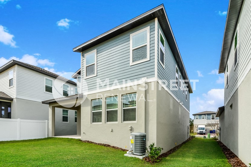 a side view of a grey house with a green lawn