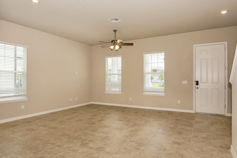 an empty living room with a ceiling fan