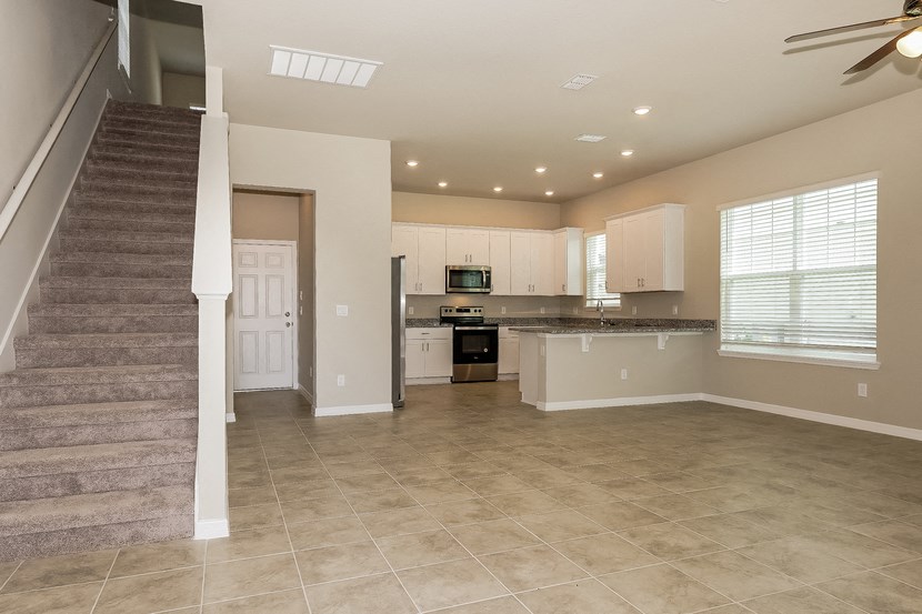 an empty kitchen and living room with a stairway to the left and a kitchen