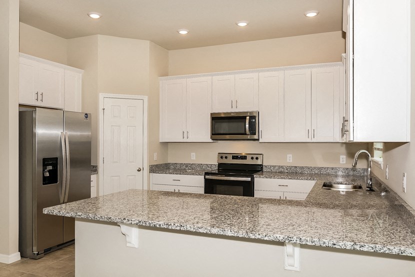 a kitchen with granite counter tops and a stainless steel refrigerator