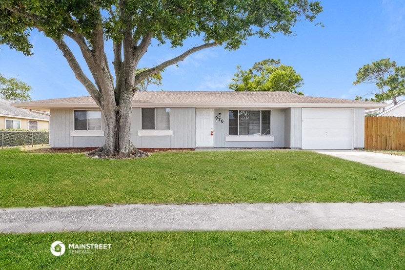 a white house with a lawn and a tree