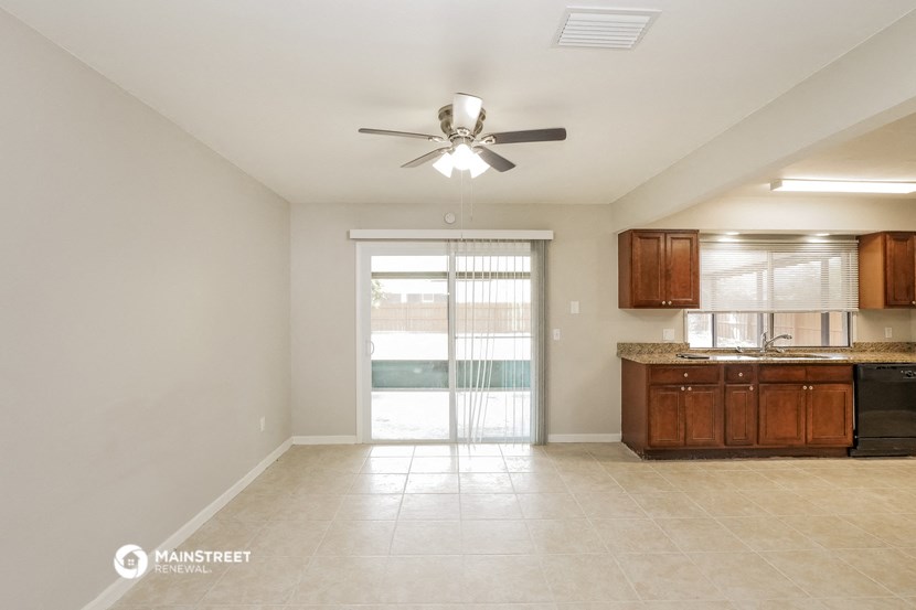 an empty kitchen with a ceiling fan and a door to a patio