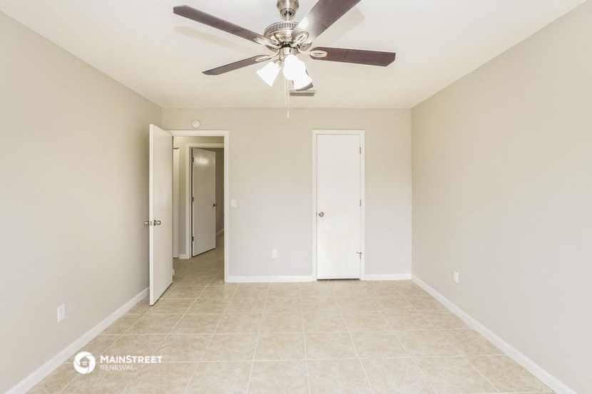 the spacious living room with ceiling fan and tile flooring