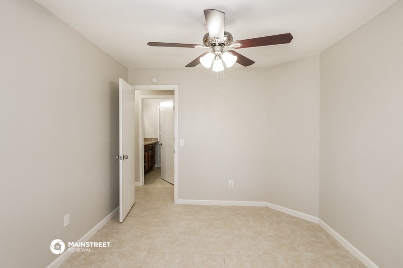 the spacious living room with ceiling fan and tile flooring
