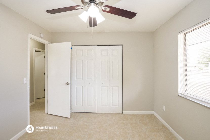 an empty bedroom with a ceiling fan and a closet