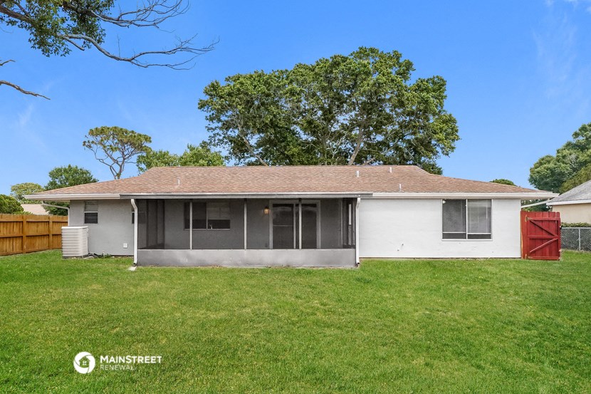 a small white house with a grassy yard and a tree