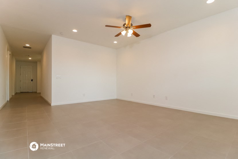 a living room with white walls and a ceiling fan