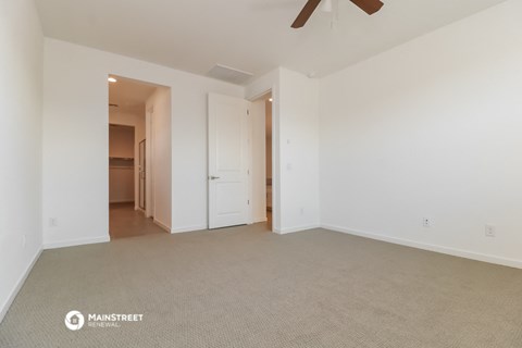 a spacious living room with carpet and a ceiling fan