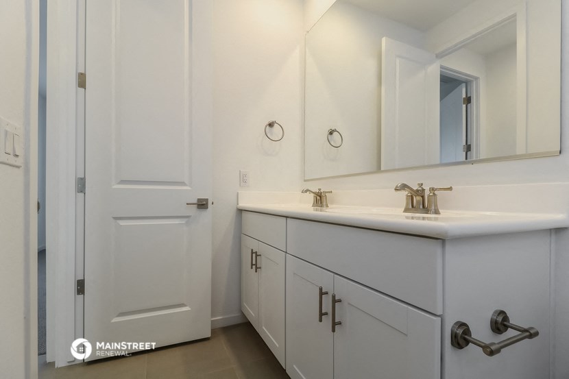 a bathroom with white cabinets and a sink and a mirror