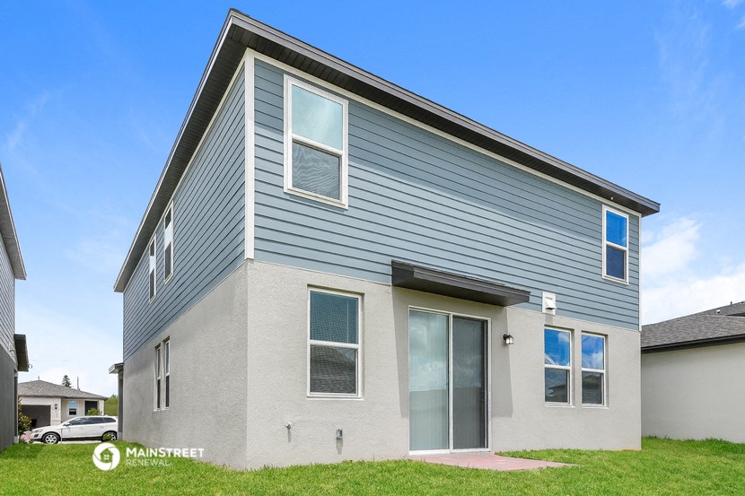 a gray house with a blue roof and a green lawn