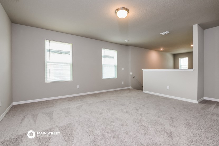 the spacious living room with white carpet and two windows