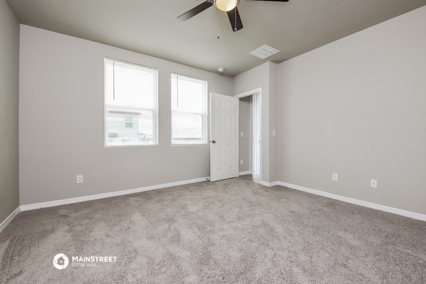 the living room of a new home with carpet and a ceiling fan