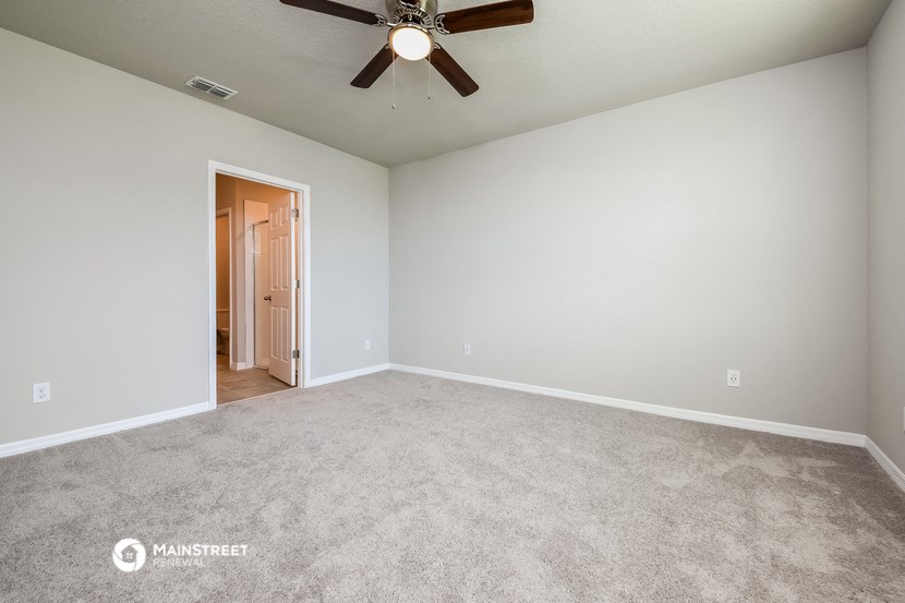 the spacious living room with carpeting and a ceiling fan