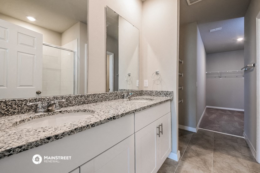 a bathroom with white cabinets and granite counter tops and a large mirror