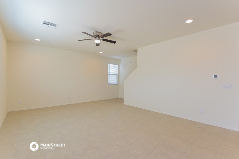 an empty living room with a ceiling fan and a tiled floor