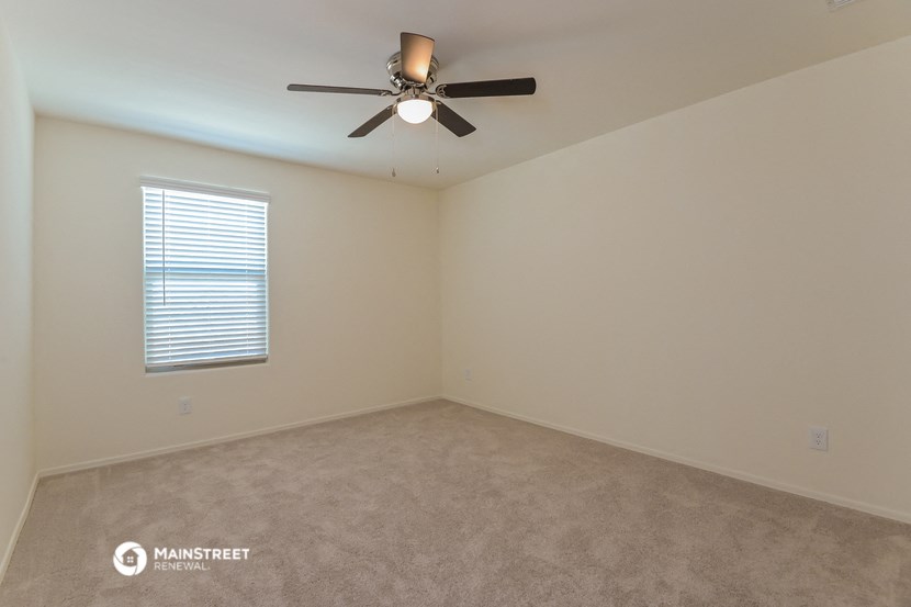 the spacious living room with ceiling fan and carpeting