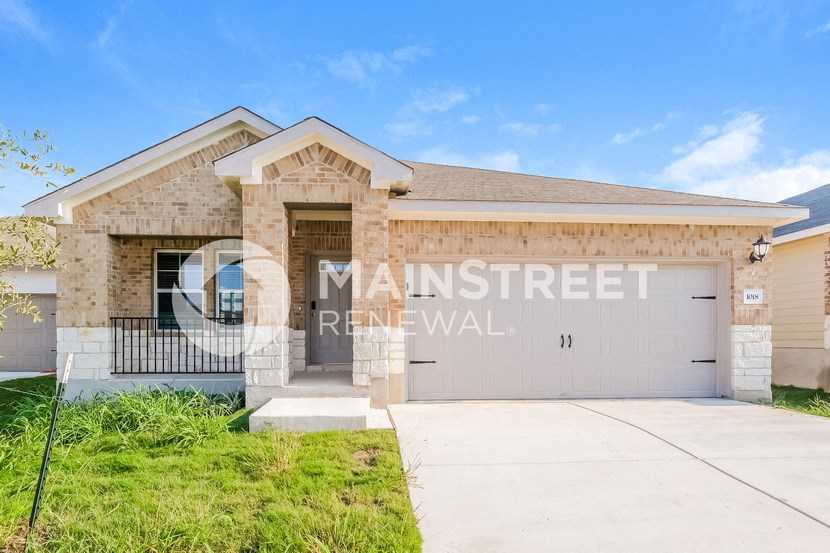 a home with a garage door and a brick house