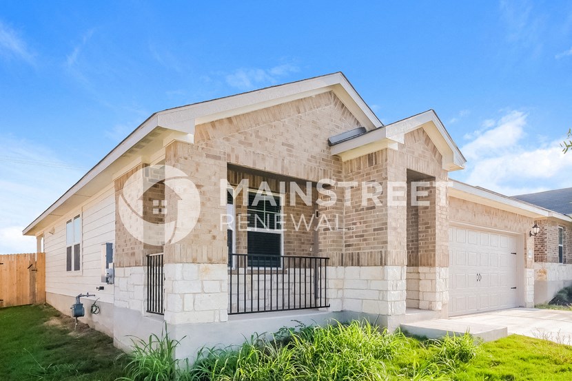 a house with a garage and a stone building with a grass yard