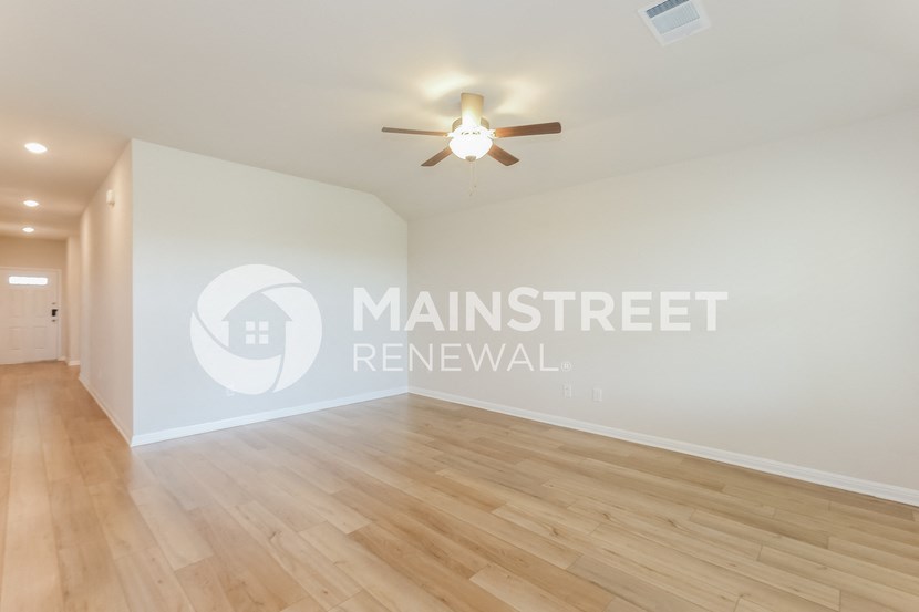 a renovated living room with hardwood floors and a ceiling fan