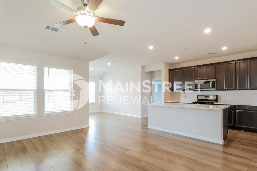 a large living room with a kitchen and a ceiling fan