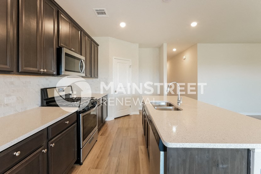 a large kitchen with a large counter top and a stainless steel stove and microwave