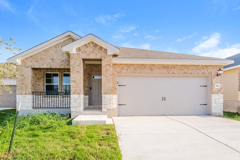 a tan brick house with a garage door and a driveway