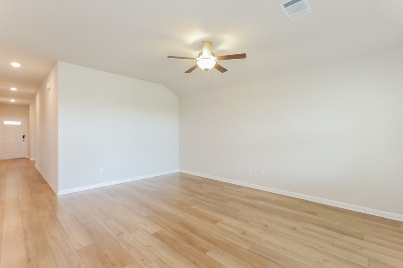 an empty living room with white walls and a ceiling fan